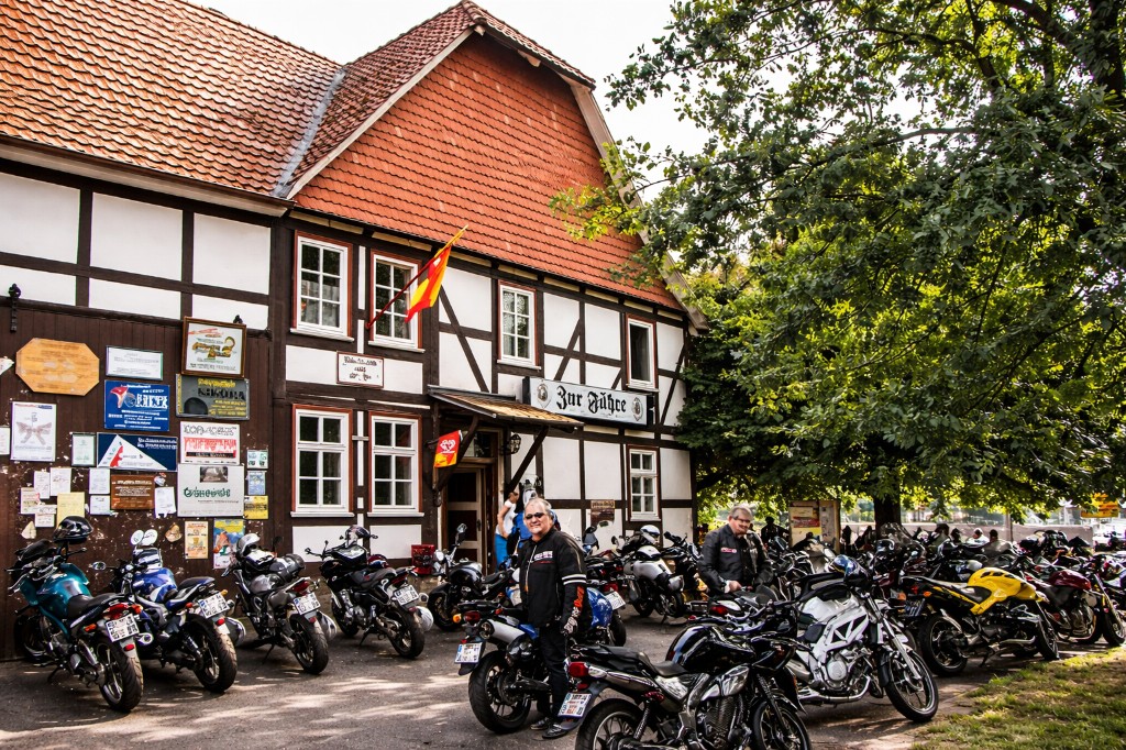 Motorradfahrer und zahlreiche Maschinen vor einem traditionellen Fachwerk-Gasthaus – Biker-Treffpunkt in der Region.