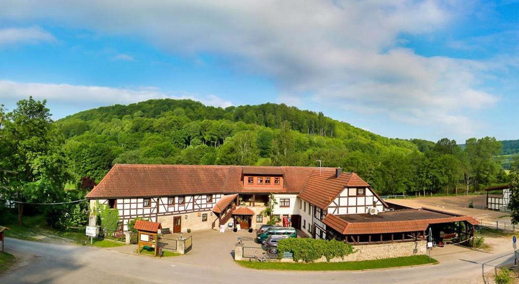 Historische Fachwerkanlage der Probstei Zella mit grünem Hügel im Hintergrund.